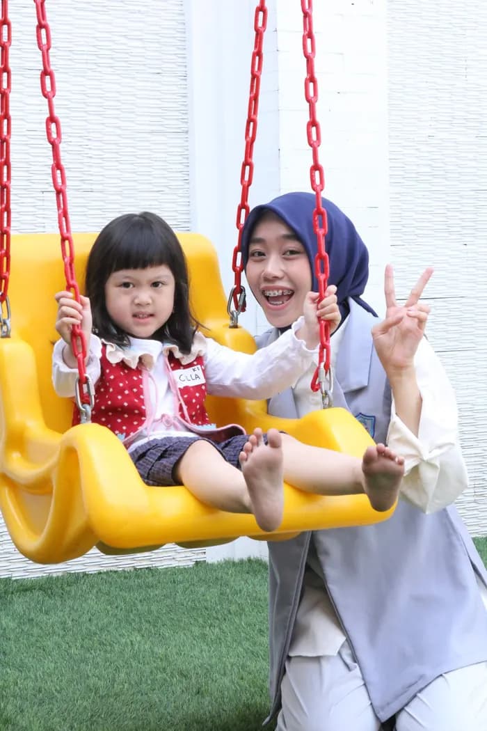 Guru dan murid bermain di area luar kelas